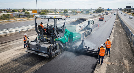 Tracked asphalt paver laying bituminous pavement